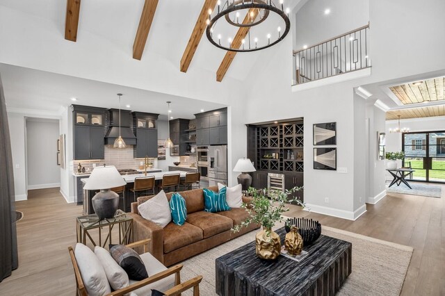 7286 Murrel Dr, Franklin, TN 37064 - living area with a chandelier, baseboards, beverage cooler, light wood-type flooring, and high vaulted ceiling
