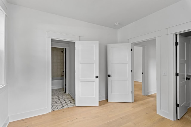 1712 Carvell Ave, Nashville, TN 37203 - unfurnished bedroom featuring light wood-style floors, baseboards, and ensuite bath
