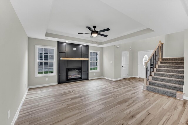 752 Boreal Way, Clarksville, TN 37042 - unfurnished living room with a tray ceiling, light wood-style floors, ceiling fan, stairs, and baseboards
