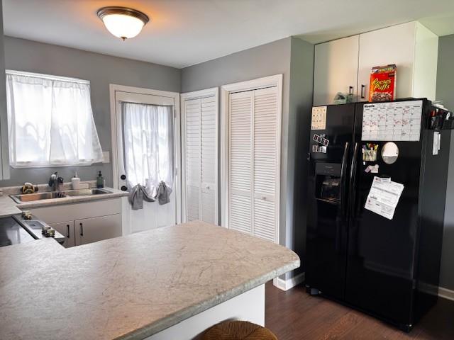 203 5th Ave N, Decherd, TN 37324 - kitchen featuring black fridge, dark wood-style floors, light countertops, and a peninsula