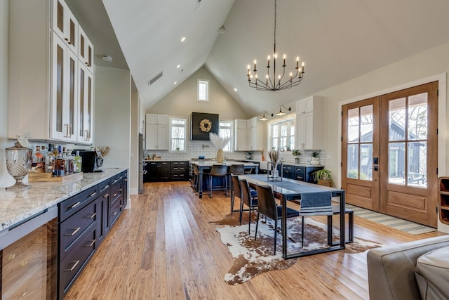 639 Piney Creek Rd, Hohenwald, TN 38462 - dining area featuring beverage cooler, a chandelier, light wood-style floors, high vaulted ceiling, and french doors