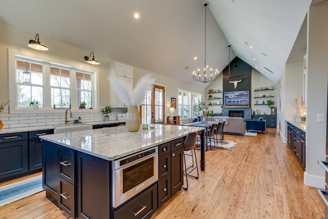 639 Piney Creek Rd, Hohenwald, TN 38462 - kitchen featuring a sink, a fireplace, high vaulted ceiling, open floor plan, and tasteful backsplash