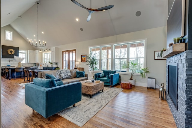 639 Piney Creek Rd, Hohenwald, TN 38462 - living room featuring high vaulted ceiling, a brick fireplace, a chandelier, and light wood-style floors
