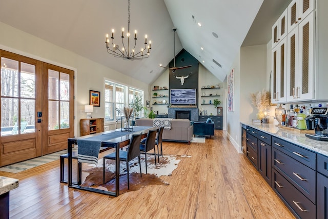 639 Piney Creek Rd, Hohenwald, TN 38462 - dining space with a fireplace, a chandelier, light wood-style floors, high vaulted ceiling, and french doors