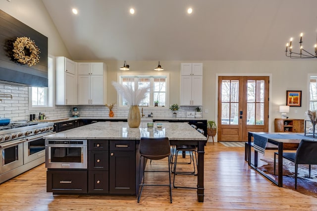 639 Piney Creek Rd, Hohenwald, TN 38462 - kitchen with stainless steel appliances, white cabinets, vaulted ceiling, decorative backsplash, and a chandelier