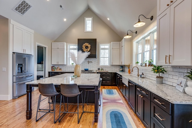 639 Piney Creek Rd, Hohenwald, TN 38462 - kitchen featuring high end refrigerator, light stone countertops, white cabinetry, a kitchen island, and high vaulted ceiling