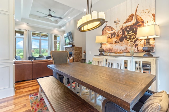 532 Tidwell Rd, Bon Aqua, TN 37025 - dining room featuring light wood-style flooring, ceiling fan, a stone fireplace, ornamental molding, and a raised ceiling