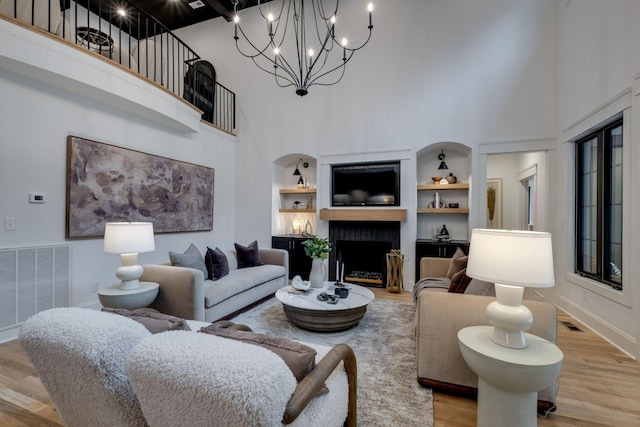 1050 Garton Rd, Burns, TN 37029 - living area with a towering ceiling, light wood-style flooring, built in features, a fireplace with raised hearth, and a chandelier