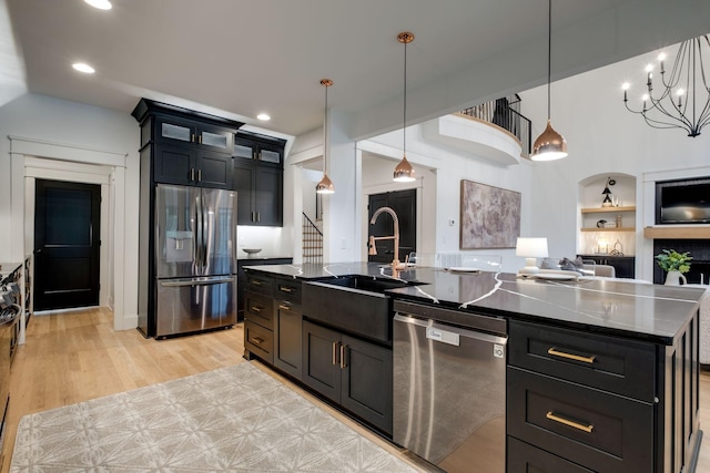 1050 Garton Rd, Burns, TN 37029 - kitchen featuring stainless steel appliances, a sink, dark cabinetry, a center island with sink, and light wood-type flooring
