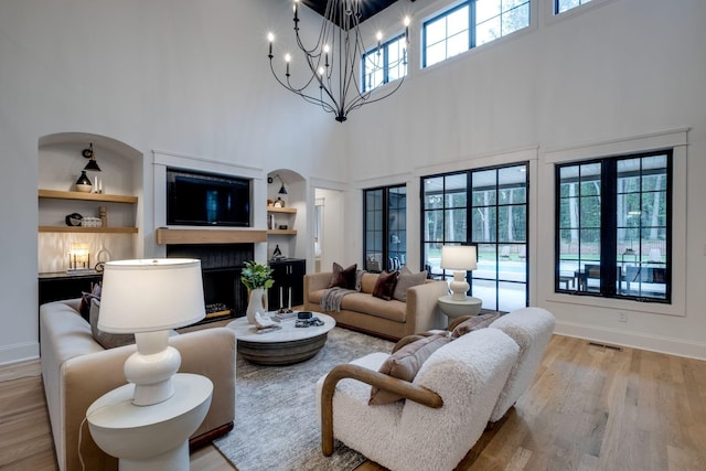 1050 Garton Rd, Burns, TN 37029 - living area with a high ceiling, built in features, light wood-style floors, a chandelier, and baseboards