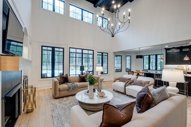 1050 Garton Rd, Burns, TN 37029 - living room with a high ceiling, light wood-type flooring, a fireplace, a chandelier, and baseboards