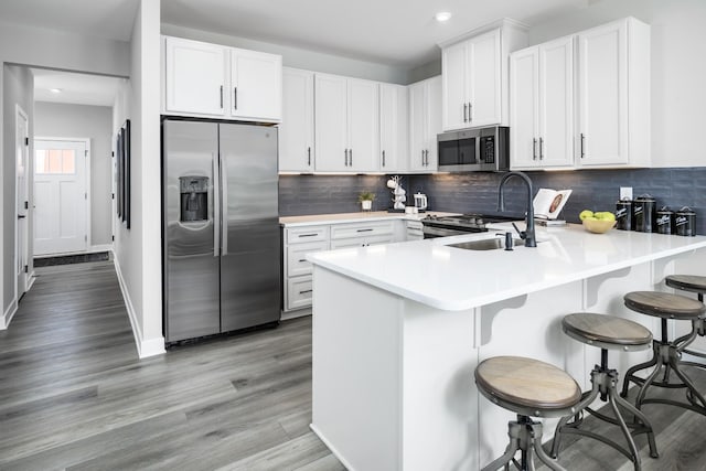 184 Primrose Ln, Gallatin, TN 37066 - kitchen featuring appliances with stainless steel finishes, a sink, a peninsula, light wood-type flooring, and light countertops