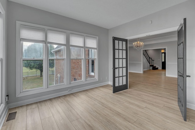 2103 Liebengood Rd, Goodlettsville, TN 37072 - spare room featuring french doors, a chandelier, light wood finished floors, stairway, and baseboards