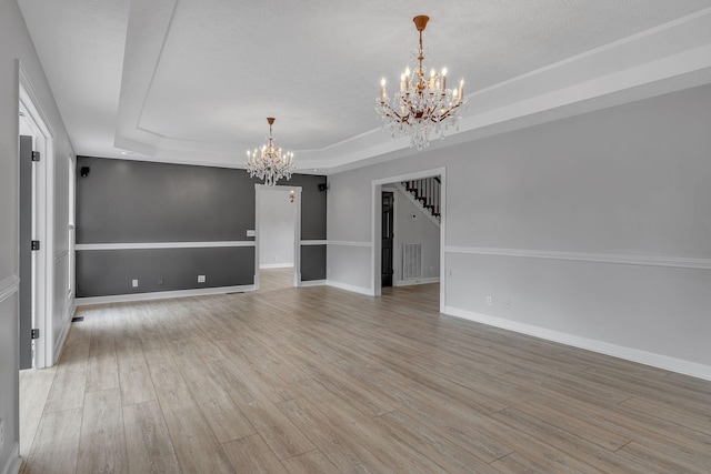 2103 Liebengood Rd, Goodlettsville, TN 37072 - spare room with a chandelier, a tray ceiling, stairs, and light wood-style flooring