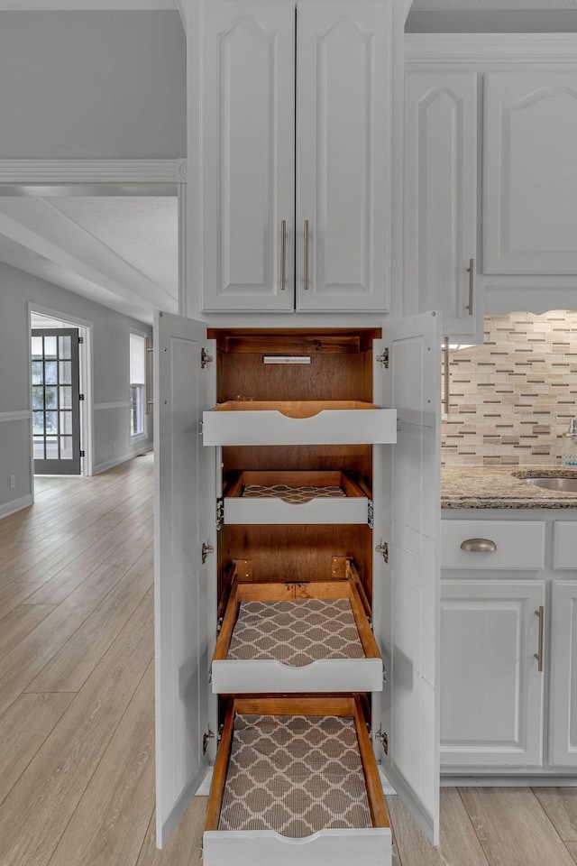 2103 Liebengood Rd, Goodlettsville, TN 37072 - detailed view of white cabinets, light wood-style flooring, tasteful backsplash, light stone countertops, and a sink