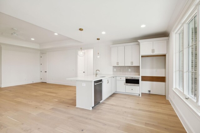 9314 Double Run Ct, College Grove, TN 37046 - kitchen with appliances with stainless steel finishes, a peninsula, light wood-style floors, decorative backsplash, and white cabinetry
