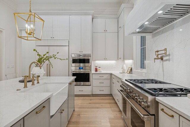 9314 Double Run Ct, College Grove, TN 37046 - kitchen with appliances with stainless steel finishes, wall chimney exhaust hood, light wood-style flooring, pendant lighting, and a sink