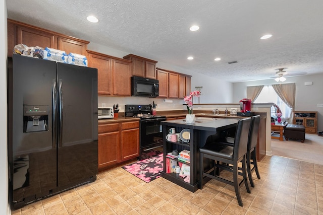 5104 Preserve Blvd, Antioch, TN 37013 - kitchen featuring black appliances, a textured ceiling, brown cabinetry, a ceiling fan, and a kitchen bar
