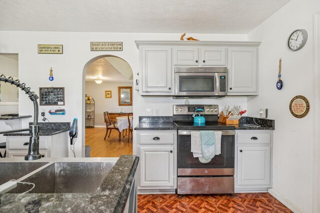 834 Union Camp Rd, Lafayette, TN 37083 - kitchen with stainless steel appliances, arched walkways, baseboards, and dark stone countertops