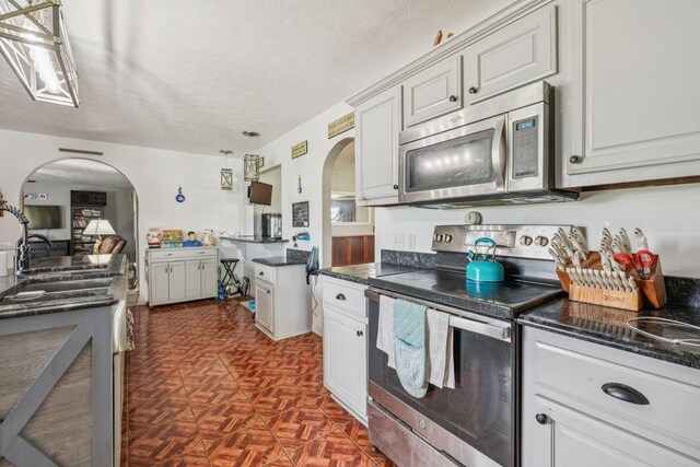 834 Union Camp Rd, Lafayette, TN 37083 - kitchen featuring appliances with stainless steel finishes, arched walkways, a sink, and a textured ceiling