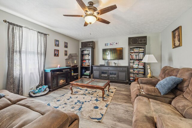 834 Union Camp Rd, Lafayette, TN 37083 - living area featuring wood finished floors, ceiling fan, a glass covered fireplace, and a textured ceiling