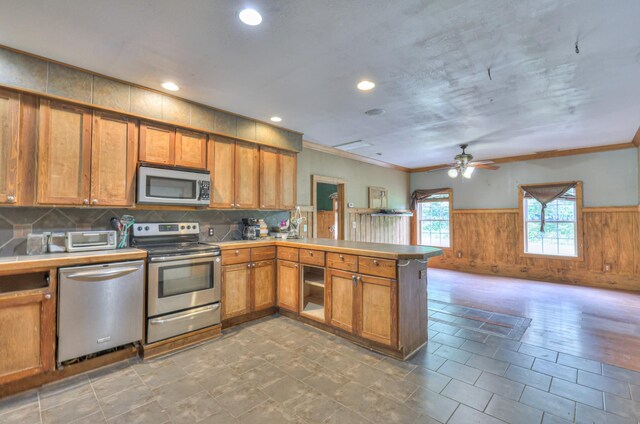 417 Haskins Chapel Rd, Lewisburg, TN 37091 - kitchen with appliances with stainless steel finishes, a peninsula, a wainscoted wall, brown cabinetry, and crown molding