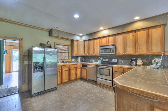 417 Haskins Chapel Rd, Lewisburg, TN 37091 - kitchen featuring appliances with stainless steel finishes, tile countertops, brown cabinets, a sink, and backsplash