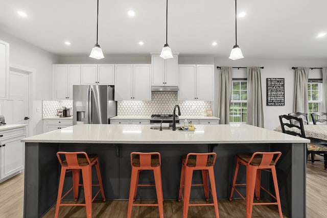 3067 Boxbury Ln, Spring Hill, TN 37174 - kitchen featuring stainless steel fridge with ice dispenser, under cabinet range hood, tasteful backsplash, white cabinetry, and recessed lighting