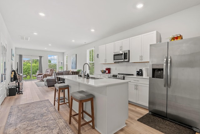 755 Mickelson Way, Lebanon, TN 37087 - kitchen featuring stainless steel appliances, open floor plan, light wood finished floors, backsplash, and white cabinets