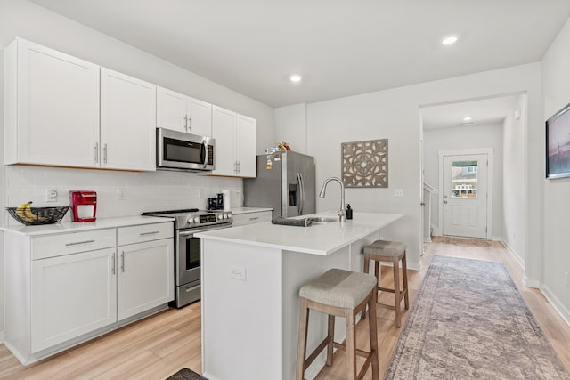 755 Mickelson Way, Lebanon, TN 37087 - kitchen featuring appliances with stainless steel finishes, light wood-type flooring, a kitchen breakfast bar, a center island with sink, and tasteful backsplash
