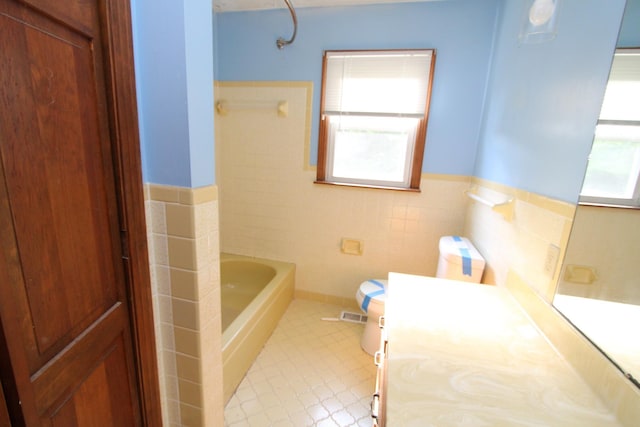 680 Oak Grove Rd, Goodspring, TN 38460 - full bath with healthy amount of natural light, toilet, a bath, tile walls, and a wainscoted wall