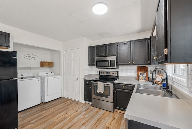 2930 Charlie Sleigh Rd, Woodlawn, TN 37191 - kitchen featuring stainless steel appliances, washer and clothes dryer, light wood-type flooring, tasteful backsplash, and light countertops