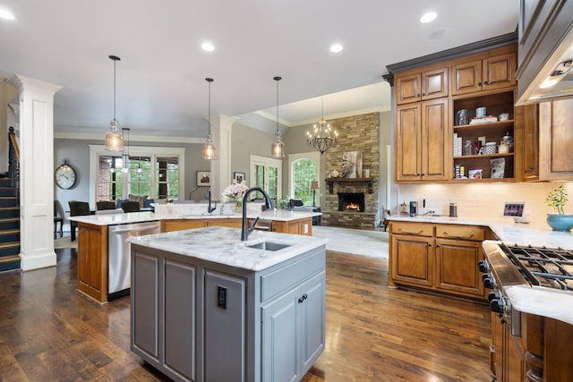 8255 Jamie Ct, Brentwood, TN 37027 - kitchen featuring stainless steel appliances, a kitchen island with sink, ornamental molding, a stone fireplace, and a sink