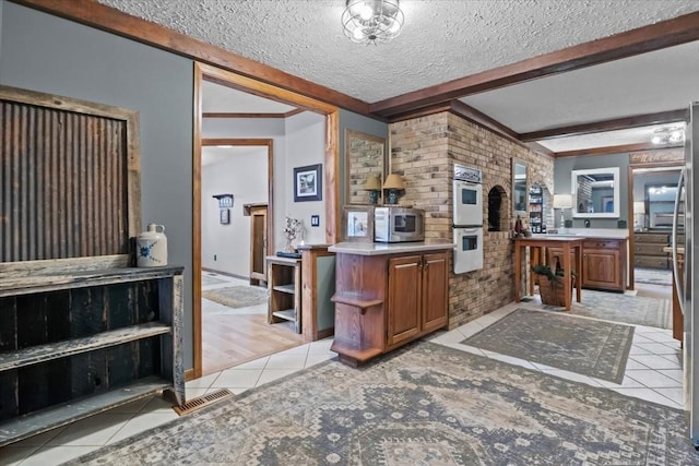 4552 Elkins Dr, Centerville, TN 37033 - kitchen featuring light tile patterned flooring, stainless steel microwave, double oven, beam ceiling, and brown cabinetry