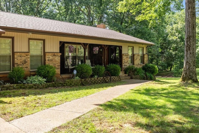 4552 Elkins Dr, Centerville, TN 37033 - view of front facade with brick siding, a chimney, a front yard, covered porch, and a shingled roof