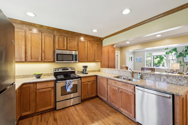 4202 Murphy Rd, Nashville, TN 37209 - kitchen featuring appliances with stainless steel finishes, a sink, a peninsula, brown cabinets, and ornamental molding