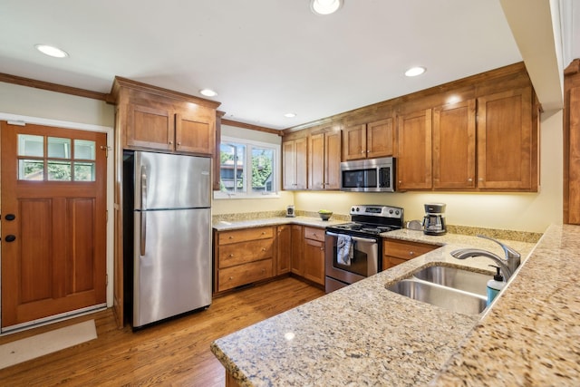4202 Murphy Rd, Nashville, TN 37209 - kitchen with appliances with stainless steel finishes, a sink, crown molding, brown cabinets, and light wood-style floors