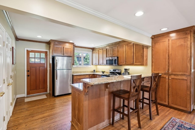 4202 Murphy Rd, Nashville, TN 37209 - kitchen with stainless steel appliances, brown cabinetry, a peninsula, crown molding, and light wood finished floors
