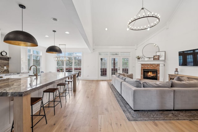 205 Well Spring Ct, Brentwood, TN 37027 - living area with a chandelier, ornamental molding, light wood-style floors, a brick fireplace, and baseboards