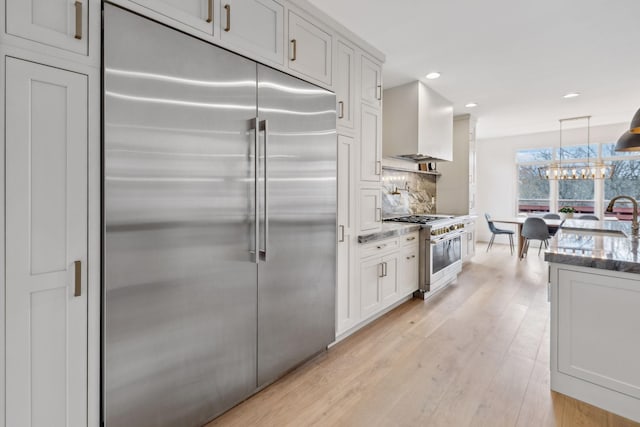205 Well Spring Ct, Brentwood, TN 37027 - kitchen with premium appliances, dark stone counters, tasteful backsplash, wall chimney range hood, and light wood-type flooring