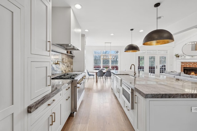205 Well Spring Ct, Brentwood, TN 37027 - kitchen with appliances with stainless steel finishes, wall chimney range hood, french doors, a sink, and white cabinets