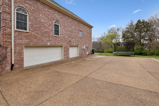 205 Well Spring Ct, Brentwood, TN 37027 - view of side of home with an attached garage, concrete driveway, brick siding, and a trampoline