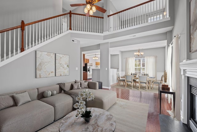 602 Pemberton Ct, Mount Juliet, TN 37122 - living room featuring wood finished floors, a chandelier, a towering ceiling, ceiling fan, and a glass covered fireplace