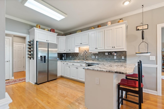 500 Forrest Park Cir, Franklin, TN 37064 - kitchen featuring stainless steel fridge with ice dispenser, white cabinets, light wood finished floors, a kitchen breakfast bar, and ornamental molding