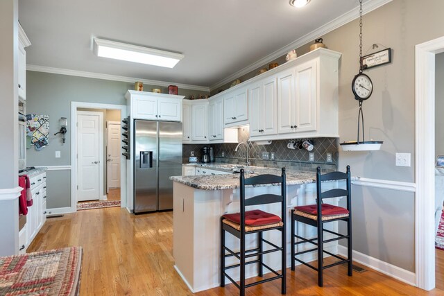 500 Forrest Park Cir, Franklin, TN 37064 - kitchen featuring stainless steel refrigerator with ice dispenser, a peninsula, white cabinetry, tasteful backsplash, and a breakfast bar area
