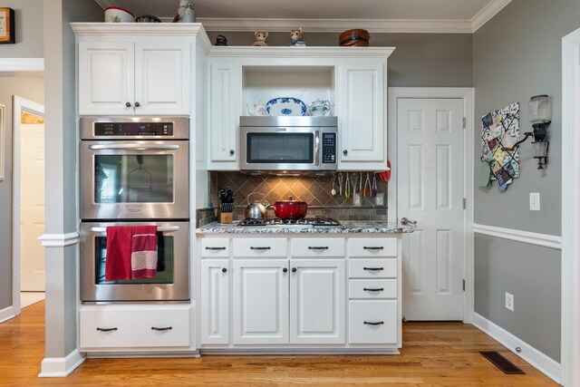 500 Forrest Park Cir, Franklin, TN 37064 - kitchen featuring stainless steel appliances, decorative backsplash, light wood-type flooring, white cabinetry, and crown molding