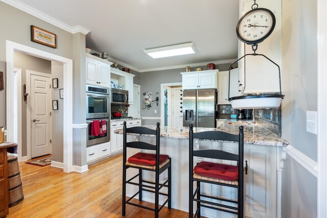 500 Forrest Park Cir, Franklin, TN 37064 - kitchen featuring appliances with stainless steel finishes, a peninsula, crown molding, light wood-type flooring, and light stone countertops