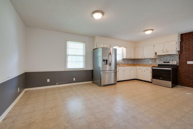 7703 Horn Tavern Rd, Fairview, TN 37062 - kitchen featuring appliances with stainless steel finishes, under cabinet range hood, white cabinetry, and light flooring