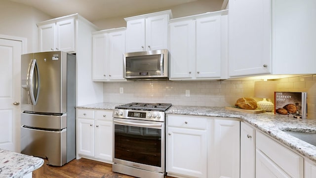2809 Kaye Dr, Thompsons Station, TN 37179 - kitchen with stainless steel appliances, white cabinetry, dark wood-type flooring, and decorative backsplash