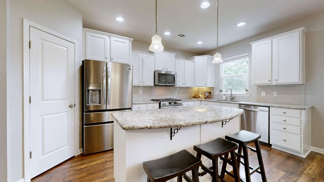 2809 Kaye Dr, Thompsons Station, TN 37179 - kitchen with appliances with stainless steel finishes, dark wood-style flooring, a kitchen island, backsplash, and white cabinetry